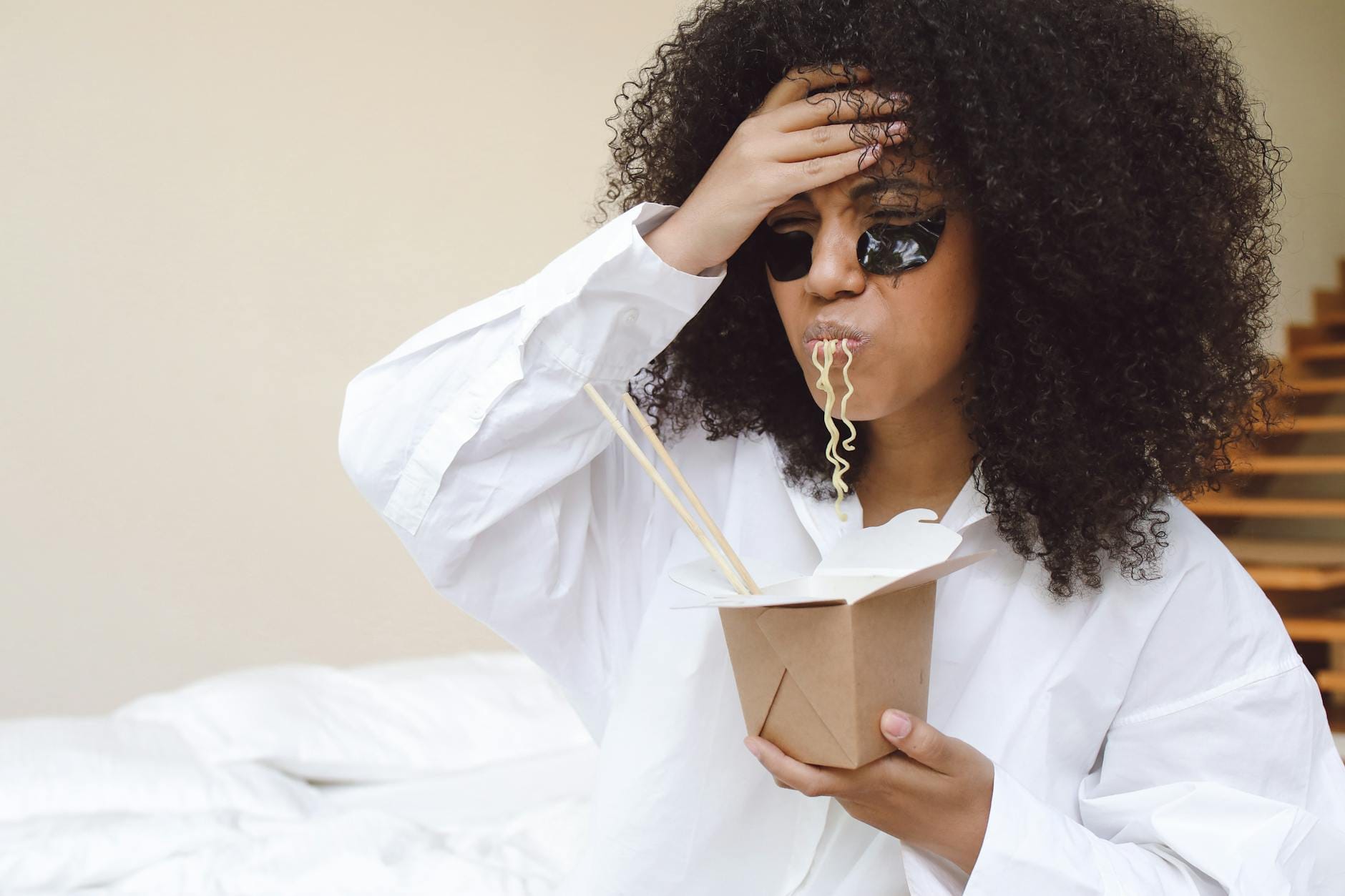 Kobieta z afro je makaron w relaksie z płatkami pod oczami