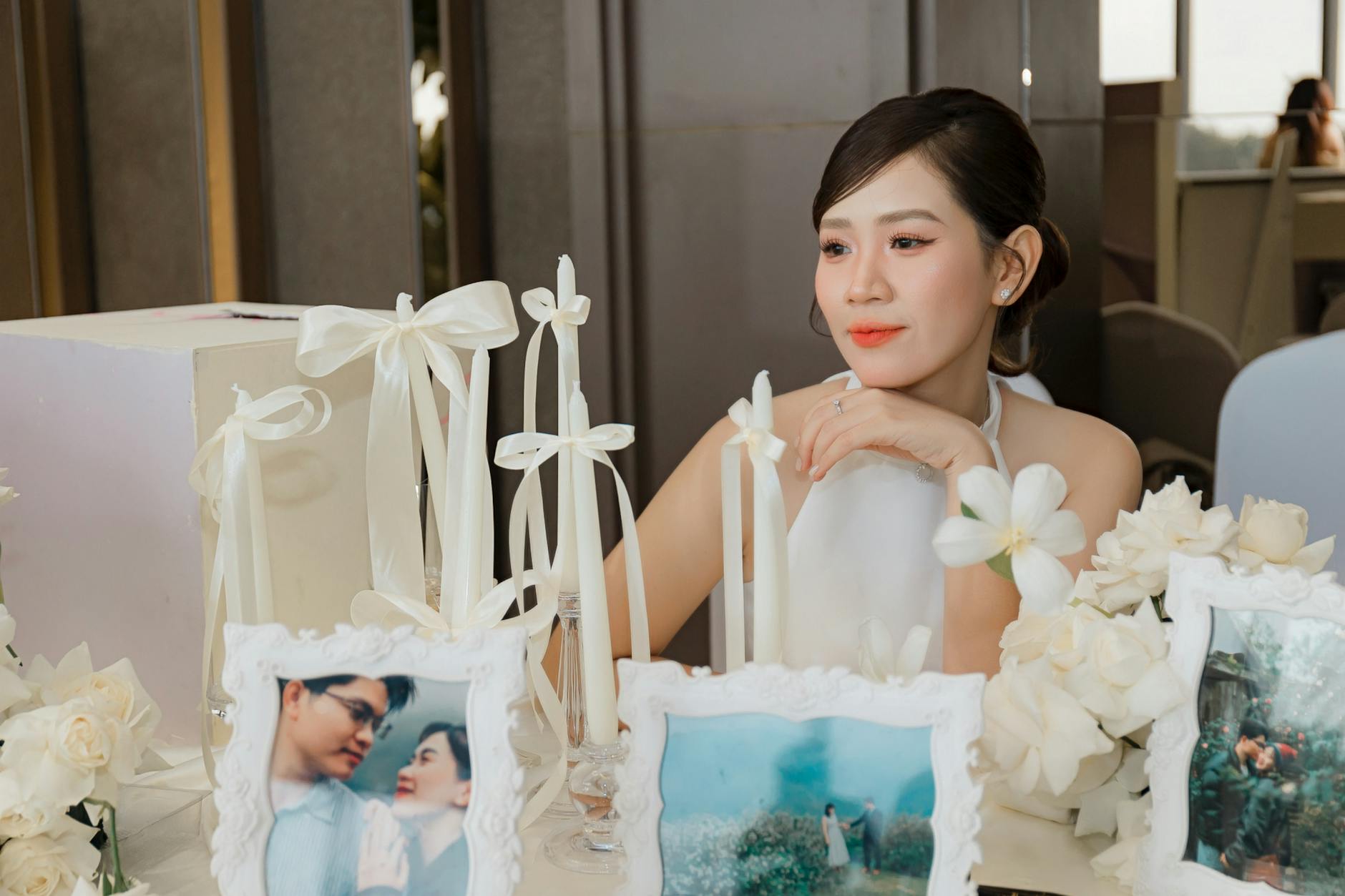 Panna młoda przy weselnym stole z świecami i rodzinnymi fotografiami