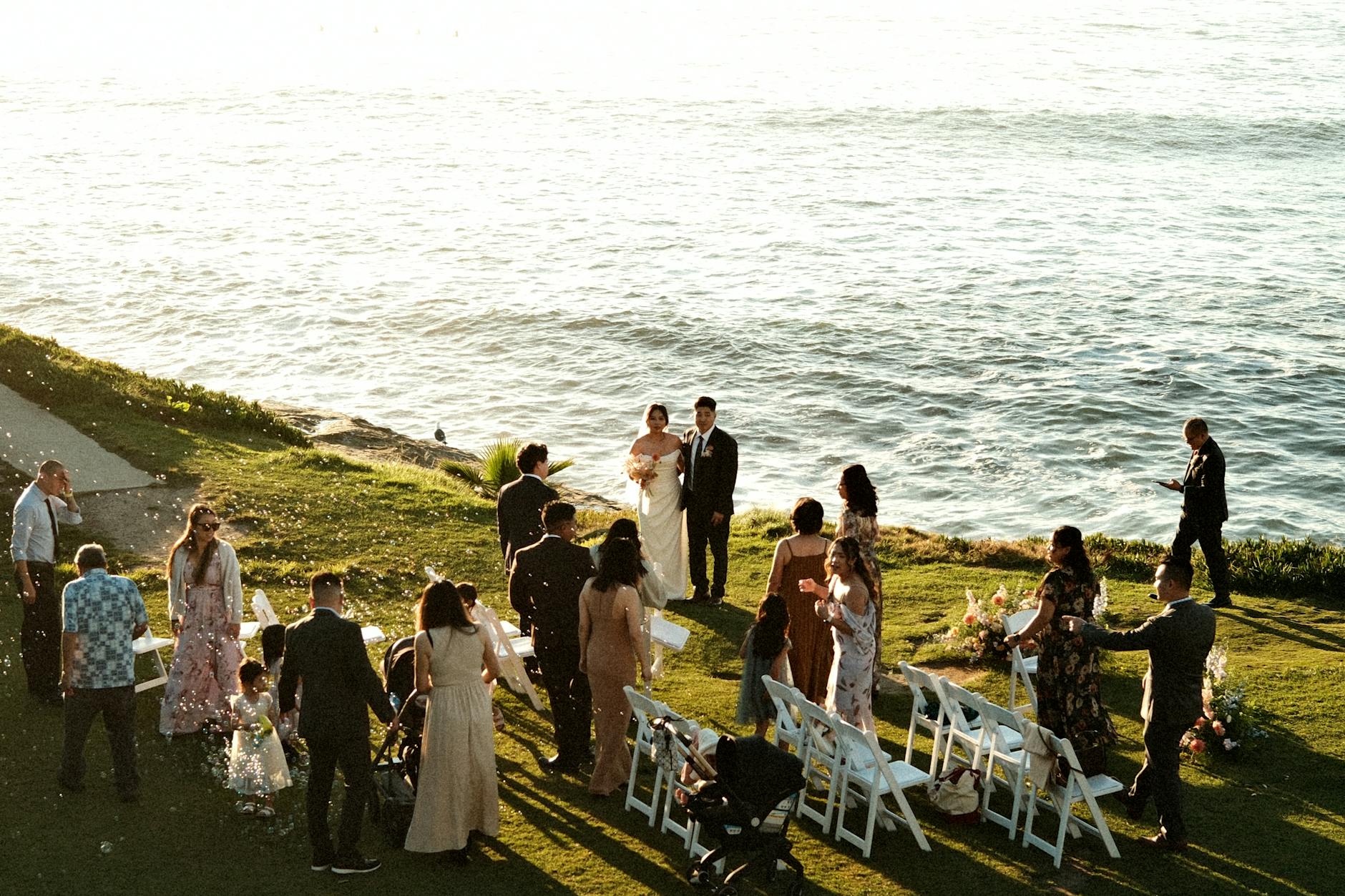 Plenerowy ślub nad morzem o zachodzie słońca z gośćmi na ceremonii